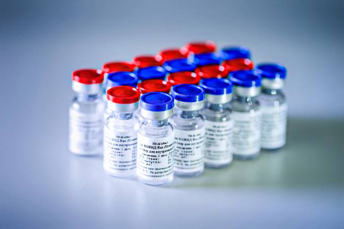 vários frascos enfileirados da vacina Sputnik V, Alguns com tampa vermelha e outros azul.